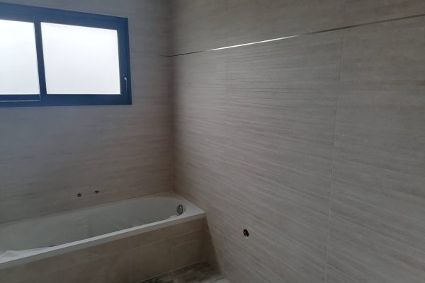 Salle de bain avec un revêtement mural en carrelage imitation bois.