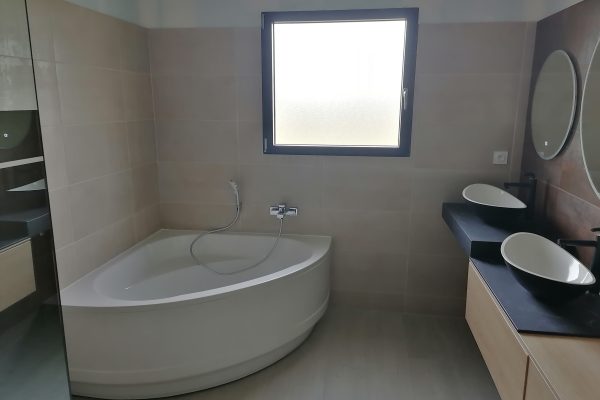 Salle de bain avec une baignoire d'angle et des vasques à poser.
