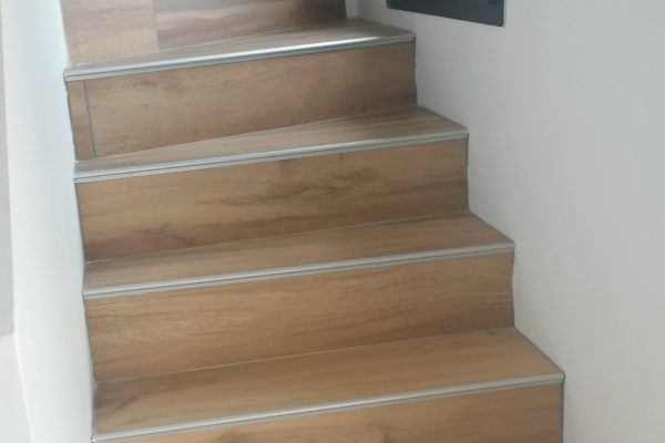 Finition avec un revêtement en carrelage imitation bois pour les marches d'escalier.